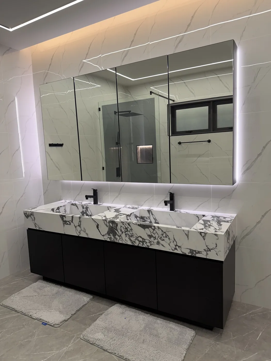 Double marble basin with backlit mirror cabinet at night